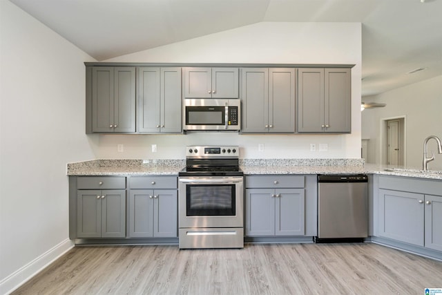 kitchen with appliances with stainless steel finishes, lofted ceiling, light hardwood / wood-style flooring, and gray cabinets