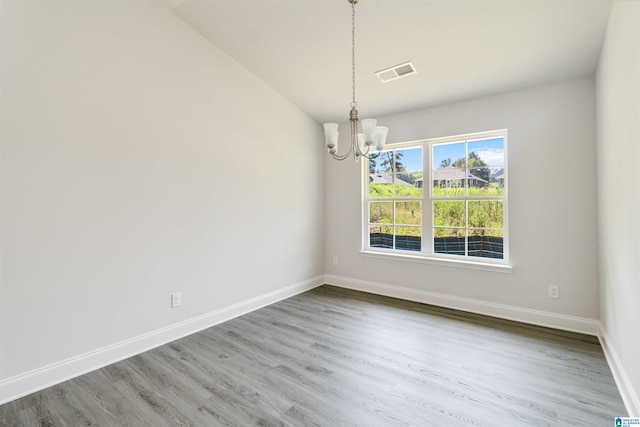 spare room featuring a notable chandelier, lofted ceiling, and hardwood / wood-style flooring