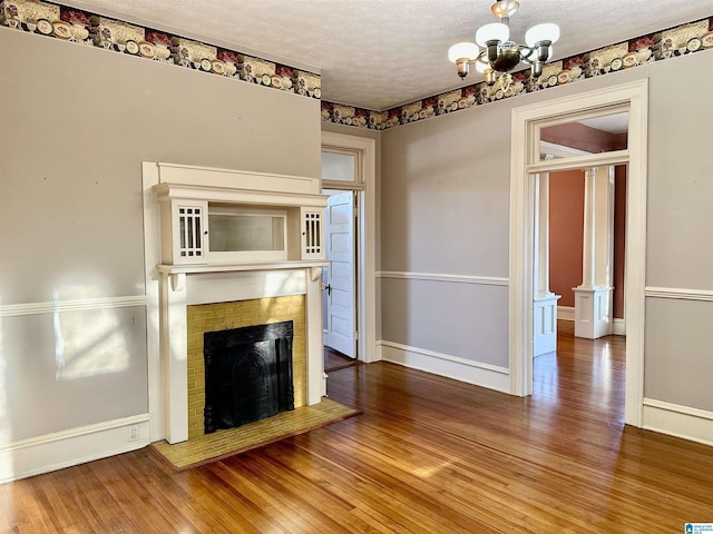 401 SW 8th St, Cullman, AL 35055 - unfurnished living room featuring a fireplace, a notable chandelier, wood finished floors, and a textured ceiling