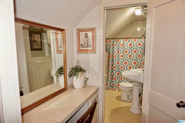 bathroom with a textured ceiling, toilet, tile patterned floors, and vaulted ceiling