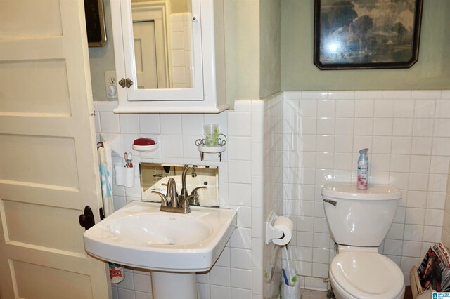 bathroom with tile walls, sink, toilet, and backsplash