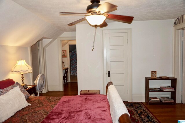 bedroom with ceiling fan, dark hardwood / wood-style flooring, a textured ceiling, and vaulted ceiling