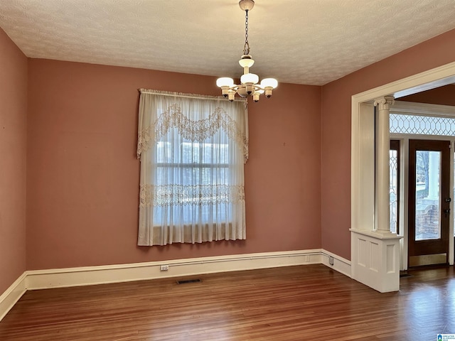 401 SW 8th St, Cullman, AL 35055 - unfurnished room featuring visible vents, wood finished floors, decorative columns, baseboards, and a chandelier