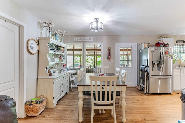 dining space with light wood finished floors and a textured ceiling