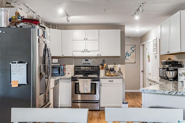 kitchen featuring light wood-type flooring, under cabinet range hood, white cabinetry, and stainless steel appliances