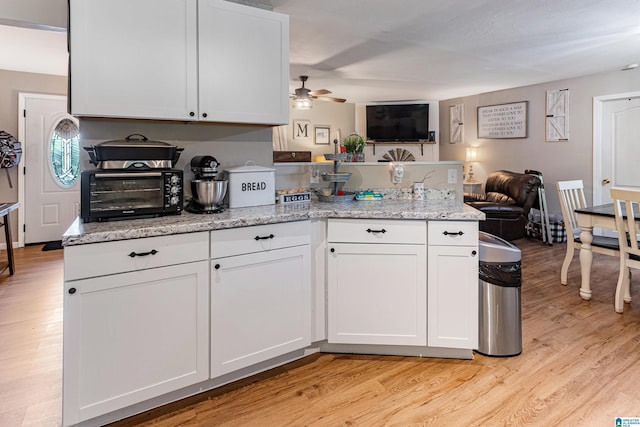 kitchen with white cabinets, light wood finished floors, light stone counters, and open floor plan