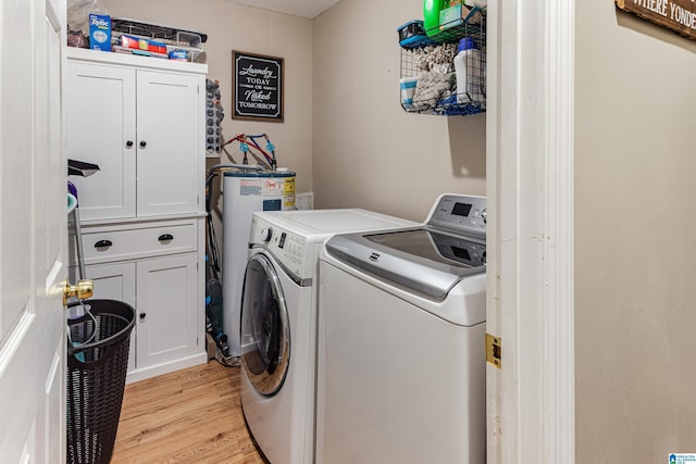 laundry area featuring cabinet space, water heater, light wood finished floors, and washer and dryer