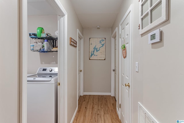 clothes washing area with washer / clothes dryer, visible vents, light wood-style floors, laundry area, and baseboards