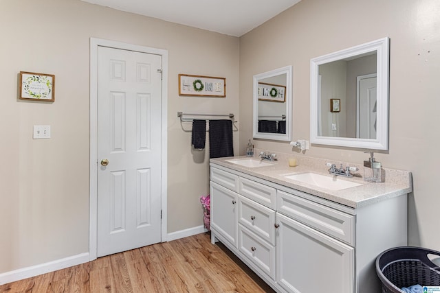 full bathroom featuring double vanity, a sink, baseboards, and wood finished floors