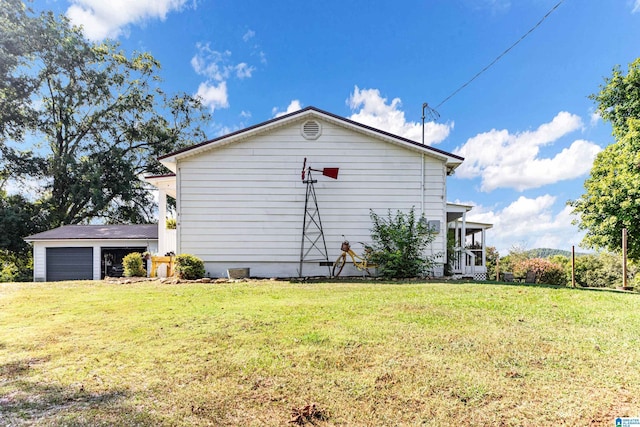 view of side of property with a garage, a lawn, and an outdoor structure