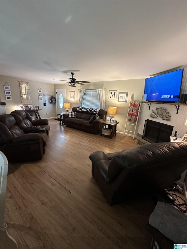 living area with ceiling fan, a fireplace, baseboards, and wood finished floors