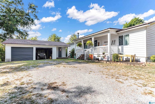 ranch-style home with covered porch, metal roof, and a detached garage