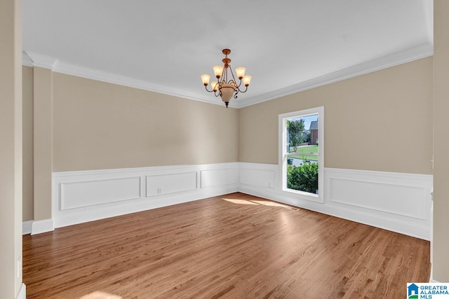 empty room featuring hardwood / wood-style floors, ornamental molding, and a notable chandelier