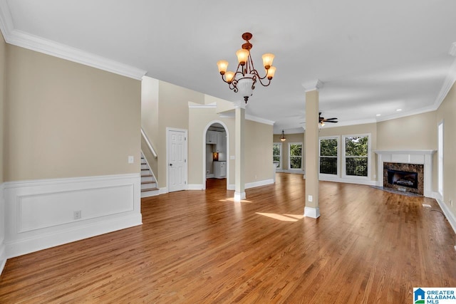 unfurnished living room featuring ceiling fan with notable chandelier, ornamental molding, a high end fireplace, and light hardwood / wood-style floors