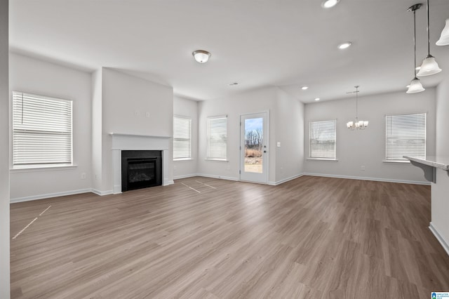 unfurnished living room featuring wood-type flooring and a chandelier