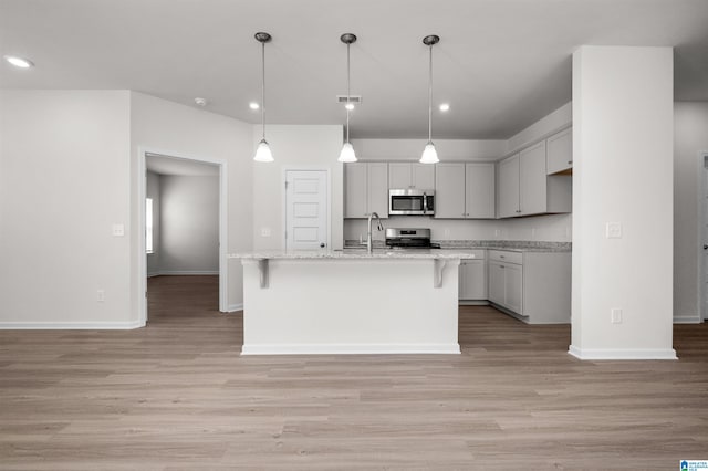 kitchen with light hardwood / wood-style flooring, an island with sink, and appliances with stainless steel finishes