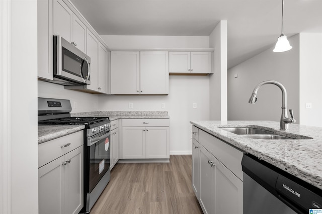 kitchen with stainless steel appliances, white cabinetry, hanging light fixtures, and sink