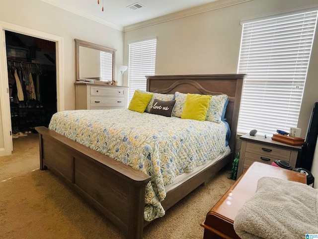 bedroom featuring a walk in closet, ornamental molding, a closet, and light carpet