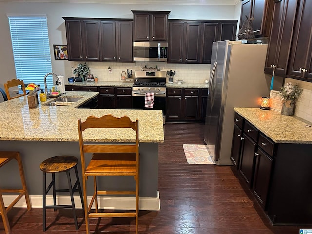 kitchen featuring a kitchen breakfast bar, dark hardwood / wood-style floors, tasteful backsplash, sink, and stainless steel appliances