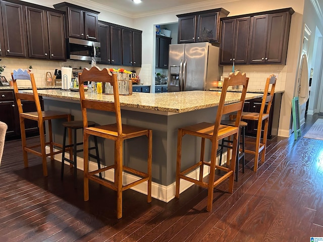 kitchen with backsplash, dark wood-type flooring, light stone countertops, crown molding, and stainless steel appliances