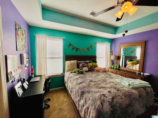 bedroom featuring ceiling fan, carpet floors, and a tray ceiling