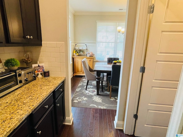 kitchen featuring light stone counters, dark wood-type flooring, crown molding, and tasteful backsplash