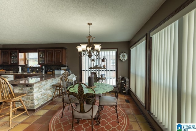 dining room featuring a textured ceiling, visible vents, a wealth of natural light, and a notable chandelier