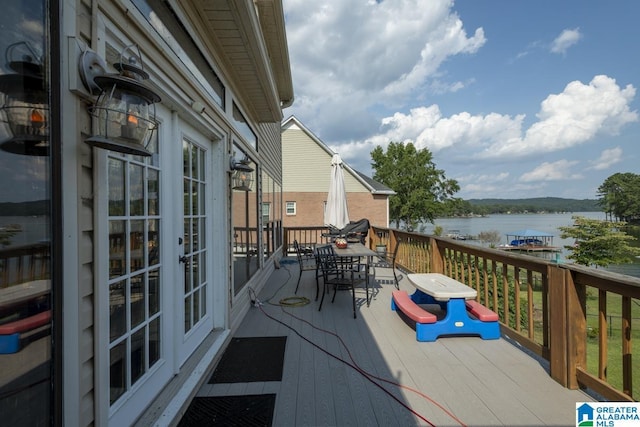 balcony with outdoor dining area and a deck with water view