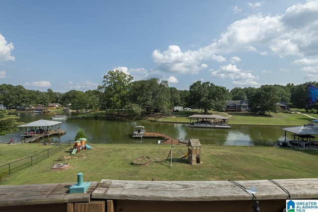 exterior space with playground community, a water view, and fence