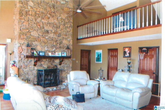 living room with a high ceiling, ceiling fan, and a stone fireplace