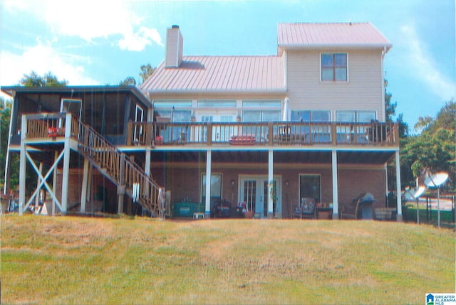 rear view of property with a chimney, a lawn, a sunroom, a wooden deck, and stairs