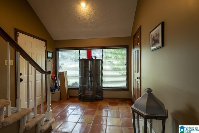 tiled entrance foyer featuring stairs, vaulted ceiling, and a textured ceiling