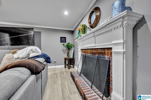 living room featuring crown molding, a brick fireplace, and light hardwood / wood-style flooring