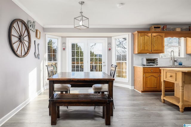 dining area with crown molding, wood-type flooring, sink, and plenty of natural light