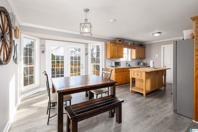 dining space featuring crown molding, sink, and light wood-type flooring