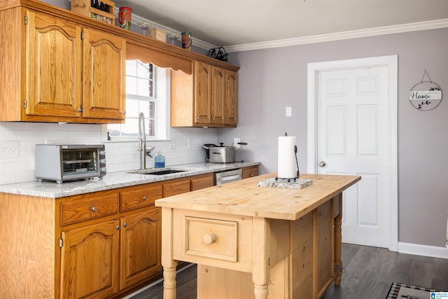 kitchen featuring a kitchen island, tasteful backsplash, sink, ornamental molding, and stainless steel dishwasher