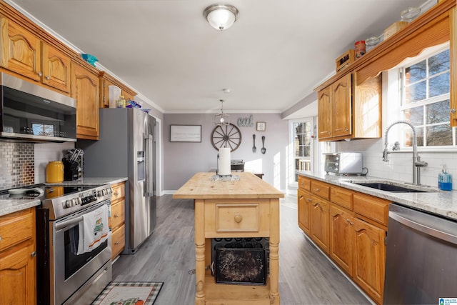 kitchen featuring sink, a center island, ornamental molding, pendant lighting, and stainless steel appliances