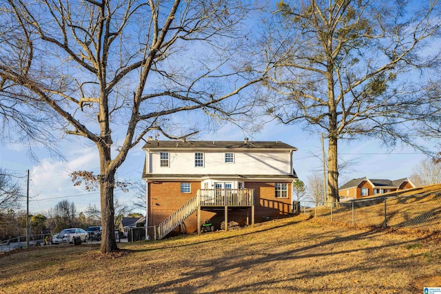 rear view of property featuring a wooden deck and a yard