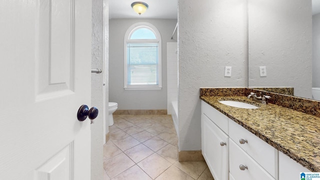 full bath with baseboards, a textured wall, toilet, tile patterned flooring, and vanity