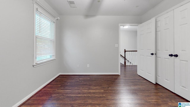 unfurnished bedroom with a closet, wood finished floors, visible vents, and baseboards