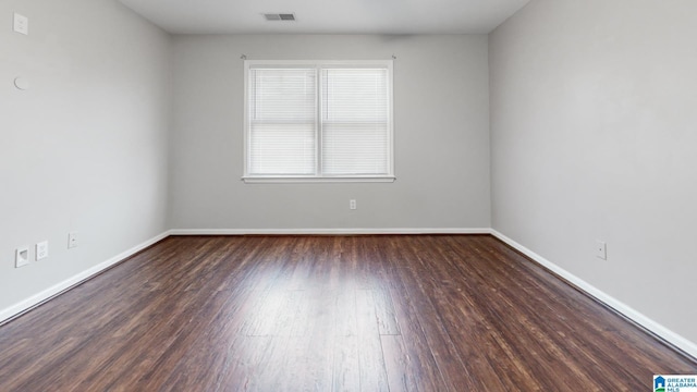 empty room featuring wood finished floors, visible vents, and baseboards