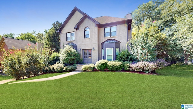 view of front of house with brick siding, a chimney, and a front yard