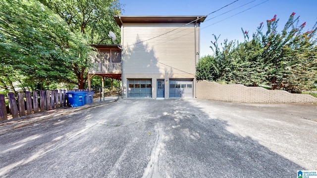 view of side of home featuring a garage, driveway, fence, and a sunroom