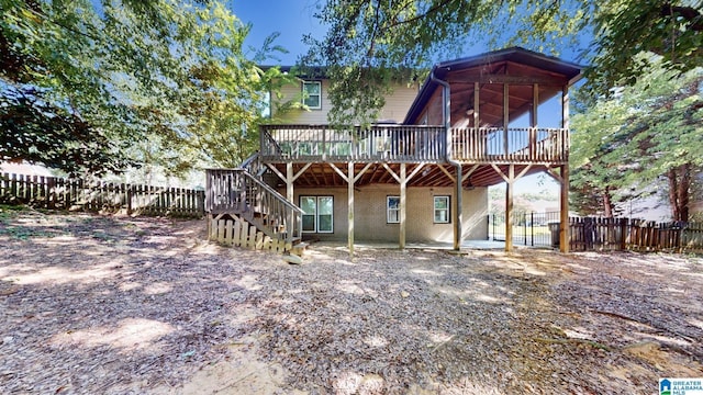 rear view of house with a deck, brick siding, stairway, and fence