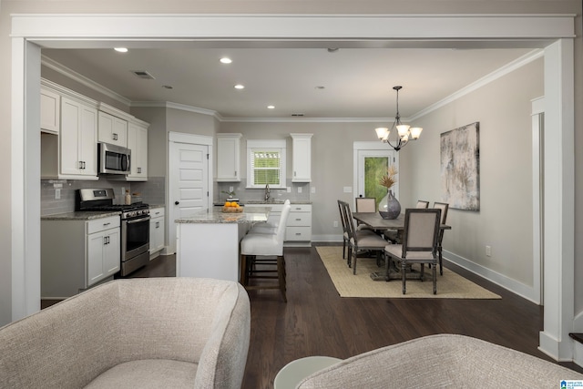 kitchen featuring dark hardwood / wood-style flooring, crown molding, stainless steel appliances, backsplash, and light stone counters