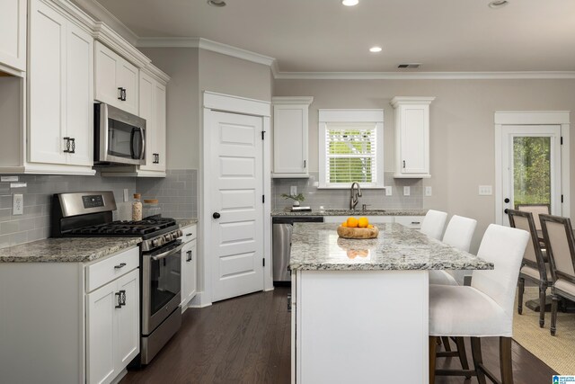 kitchen featuring dark wood-type flooring, stainless steel appliances, white cabinets, backsplash, and light stone counters