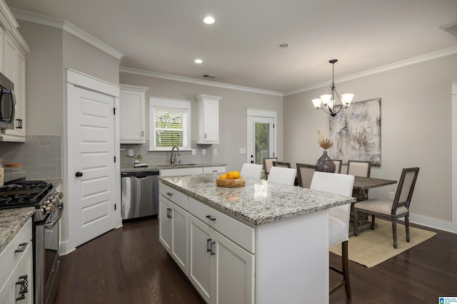 kitchen featuring sink, white cabinetry, decorative light fixtures, a center island, and stainless steel appliances