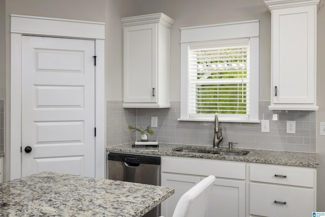 kitchen with white cabinets, light stone countertops, stainless steel dishwasher, tasteful backsplash, and sink