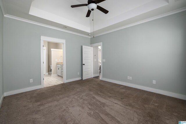 unfurnished bedroom featuring light tile patterned floors, connected bathroom, and a raised ceiling