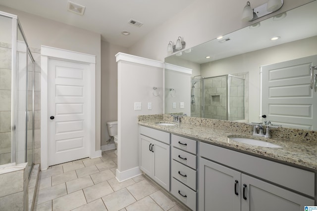 bathroom with dual vanity, toilet, a shower with door, and tile patterned flooring